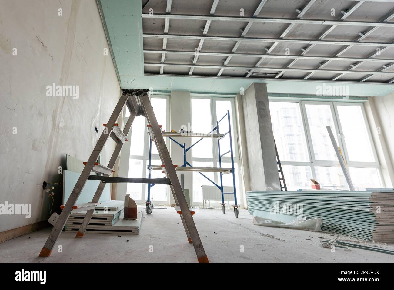 Les travailleurs installent des plaques de plâtre (cloisons sèches) pour les murs de gypse dans l'appartement est en construction, remodelage, rénovation, extension, restauration et Banque D'Images