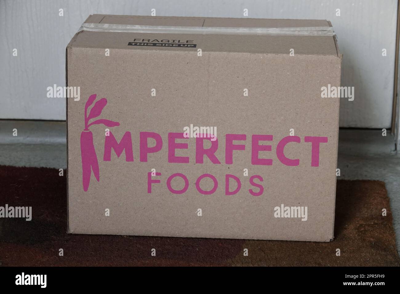 Los Angeles, Californie / Etats-Unis - 22 avril 2023: Une boîte de carton de livraison de produits alimentaires imparfaits est montrée à l'extérieur d'une porte d'entrée résidentielle. Pour edito Banque D'Images