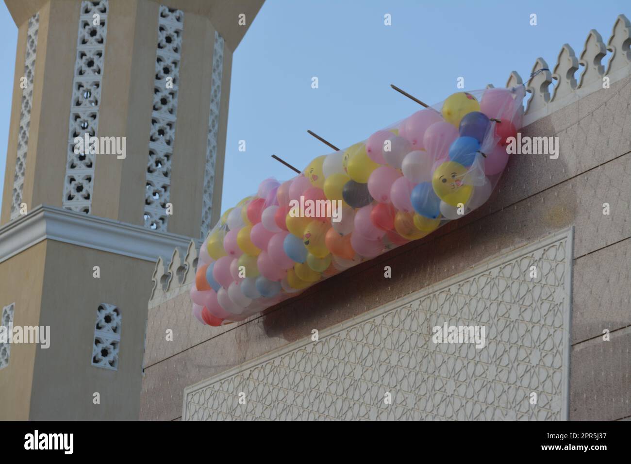 Contexte de fête et de célébrations à l'extérieur d'une mosquée au Caire Egypte avec des dizaines de ballons tenus dans le toit de la mosquée à côté du minaret à jeter Banque D'Images