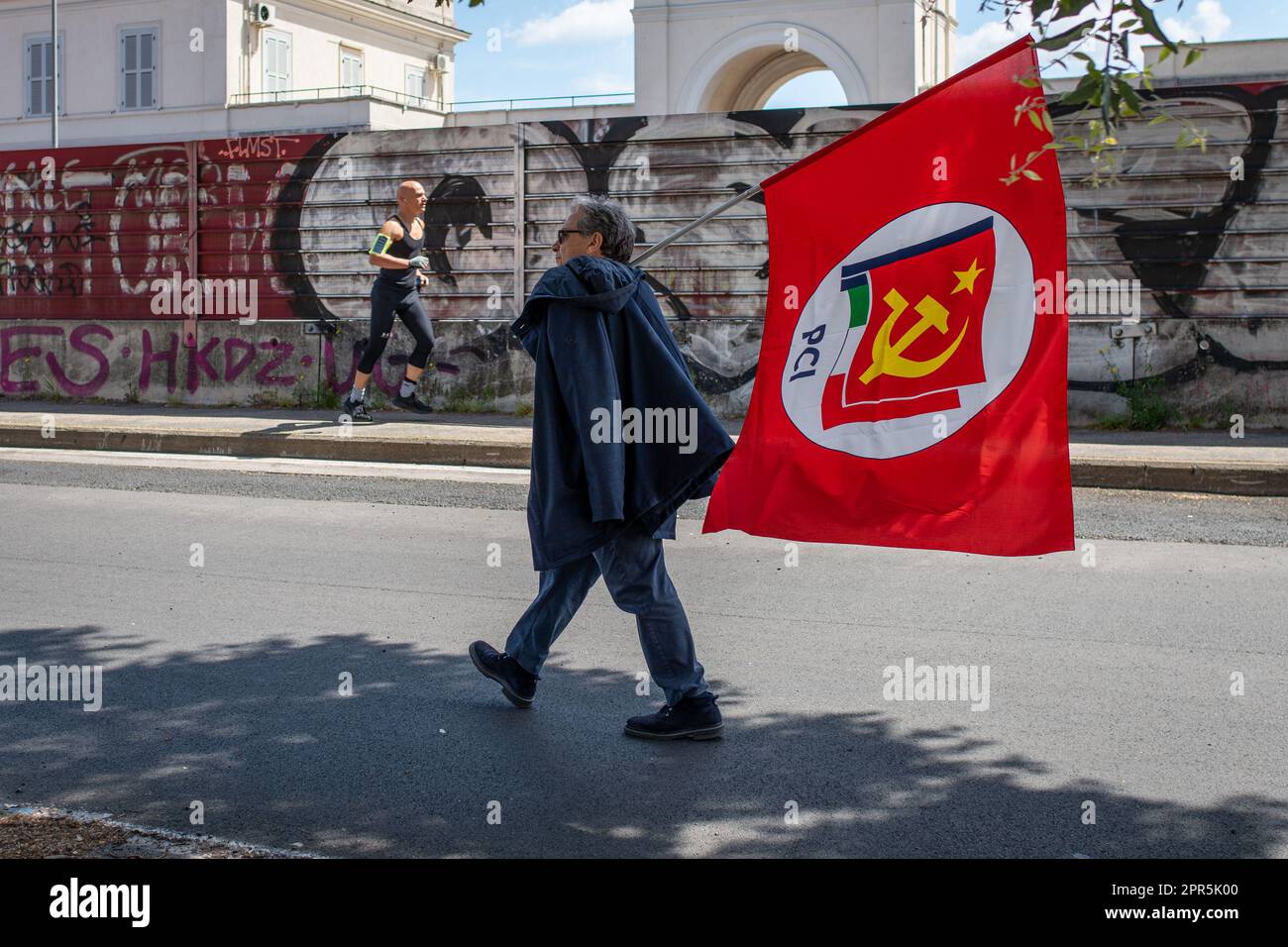 Un homme a vu marcher avec le drapeau rouge du Parti communiste italien pendant la manifestation. Environ 10 mille manifestants ont participé au défilé organisé par l'ANPI (Association nationale des partisans d'Italie) à Rome à l'occasion du 78th anniversaire de la libération du fascisme nazi. En partant de Largo Bompiani, ils ont traversé les quartiers de Tor Marancia, Garbatella et Ostiense, jusqu'à leur arrivée à Porta San Paolo. La manifestation s'est terminée à Piazzale Ostiense par des discours de personnalités politiques, de syndicats et les témoignages de ceux qui étaient partisans pendant le Banque D'Images