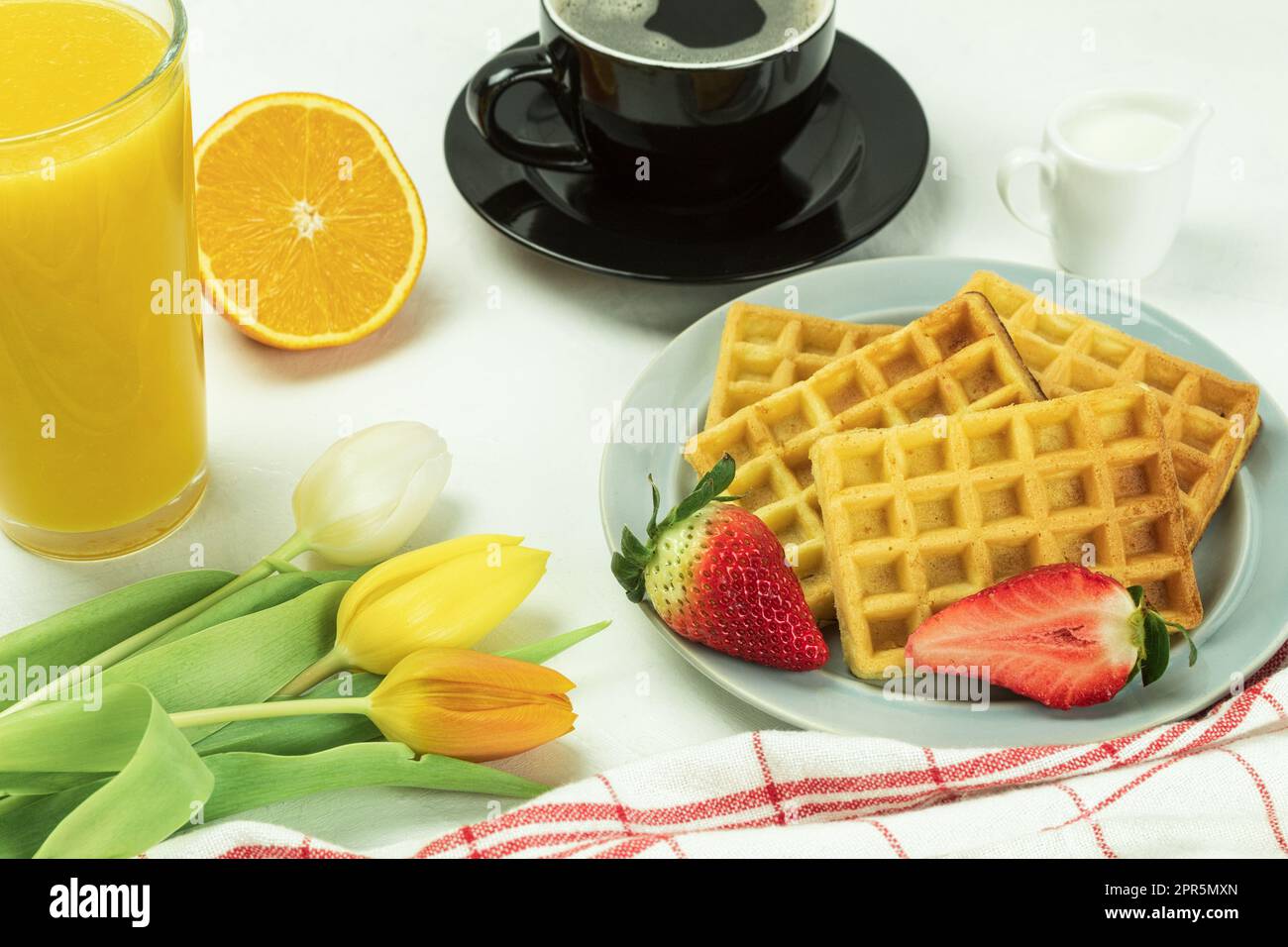 Gaufres belges et fruits frais pour le petit déjeuner. Jus d'orange frais et café avec gaufres viennoises et fleurs fraîches Banque D'Images