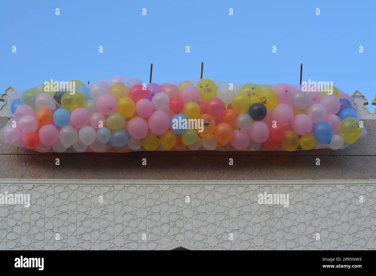 Contexte de fête et de célébrations à l'extérieur d'une mosquée au Caire Egypte avec des dizaines de ballons tenus dans le toit de la mosquée à côté du minaret à jeter Banque D'Images