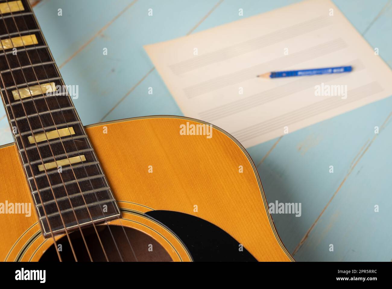 Scène d'enregistrement de musique avec guitare, feuille de musique vide et crayon sur table en bois Banque D'Images