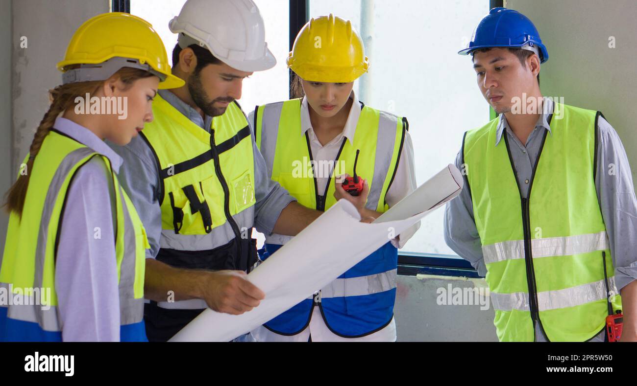 Un jeune contremaître asiatique en casque bleu et gilet de sécurité a essayé de s'y rendre pour examiner le plan de construction. Milieu de travail au chantier du projet de logement. Banque D'Images