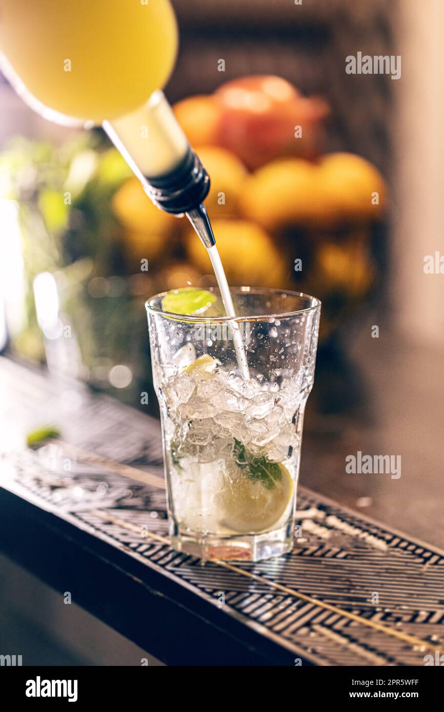 Barman versant du sirop dans un verre à cocktail Banque D'Images