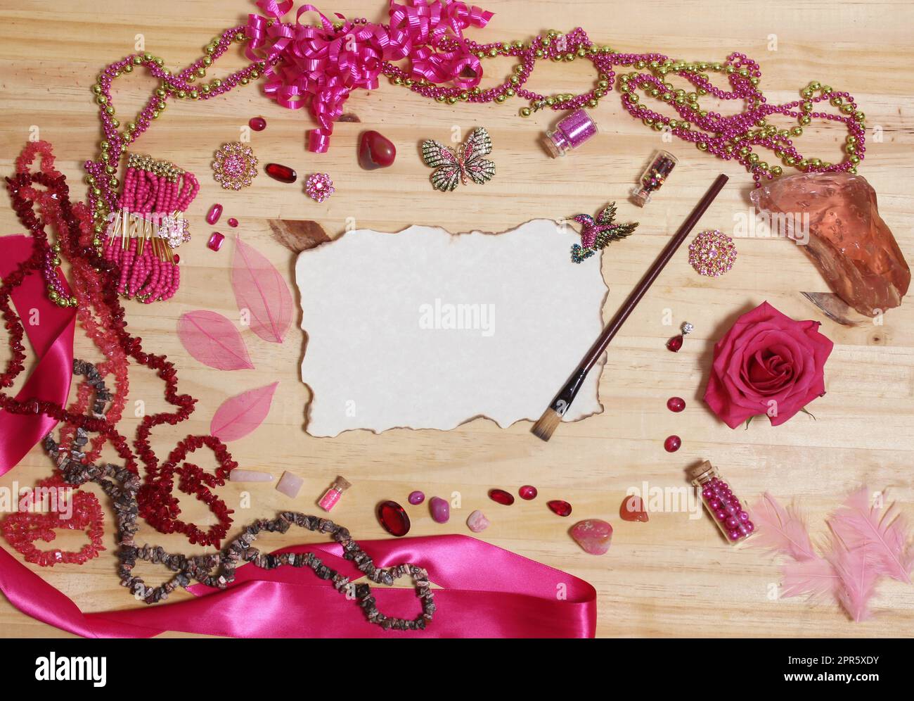 Bijoux rose et magenta avec fleur et papier vierge avec bords brûlés Banque D'Images