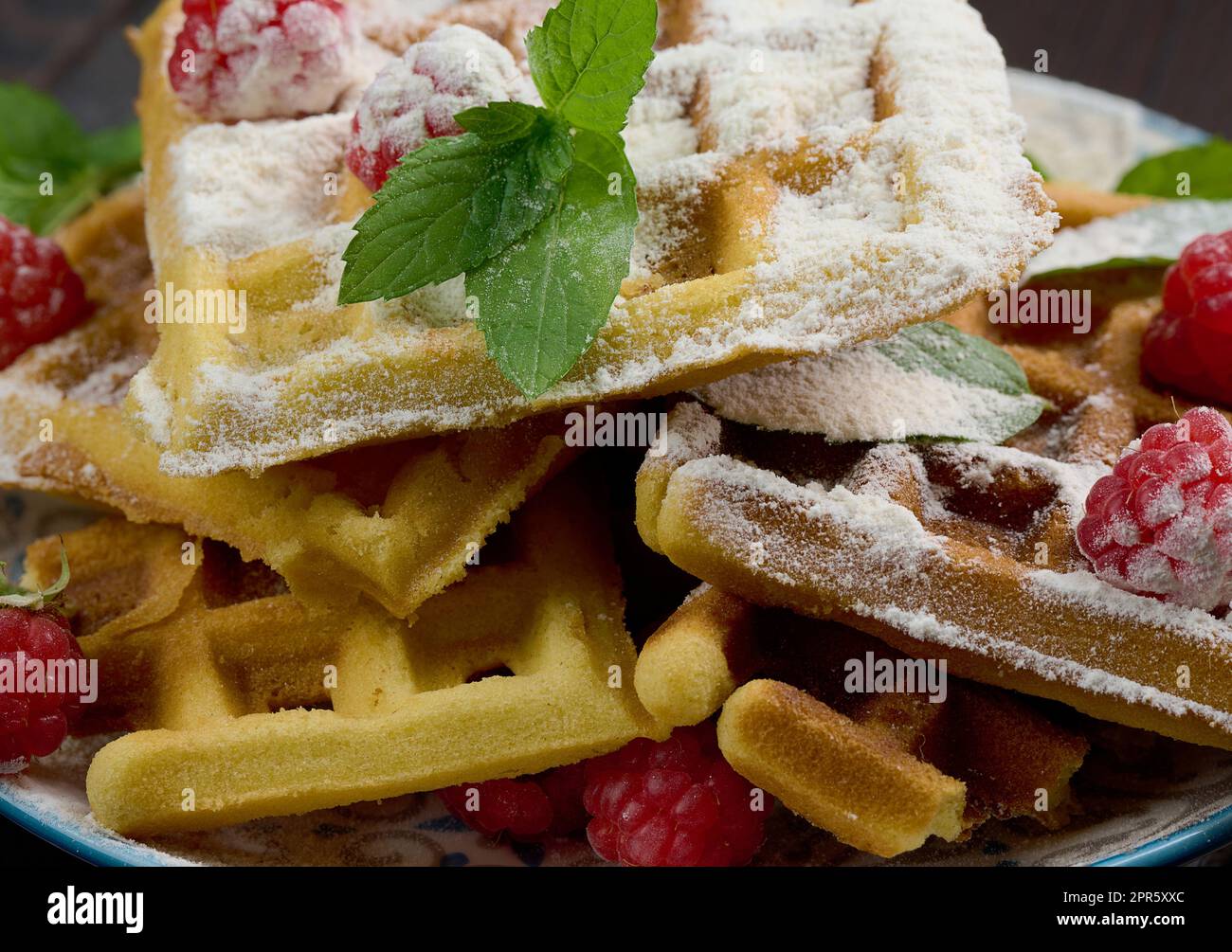 Pile de gaufres belges cuites au four avec framboises rouges mûres saupoudrées de sucre en poudre, petit déjeuner Banque D'Images