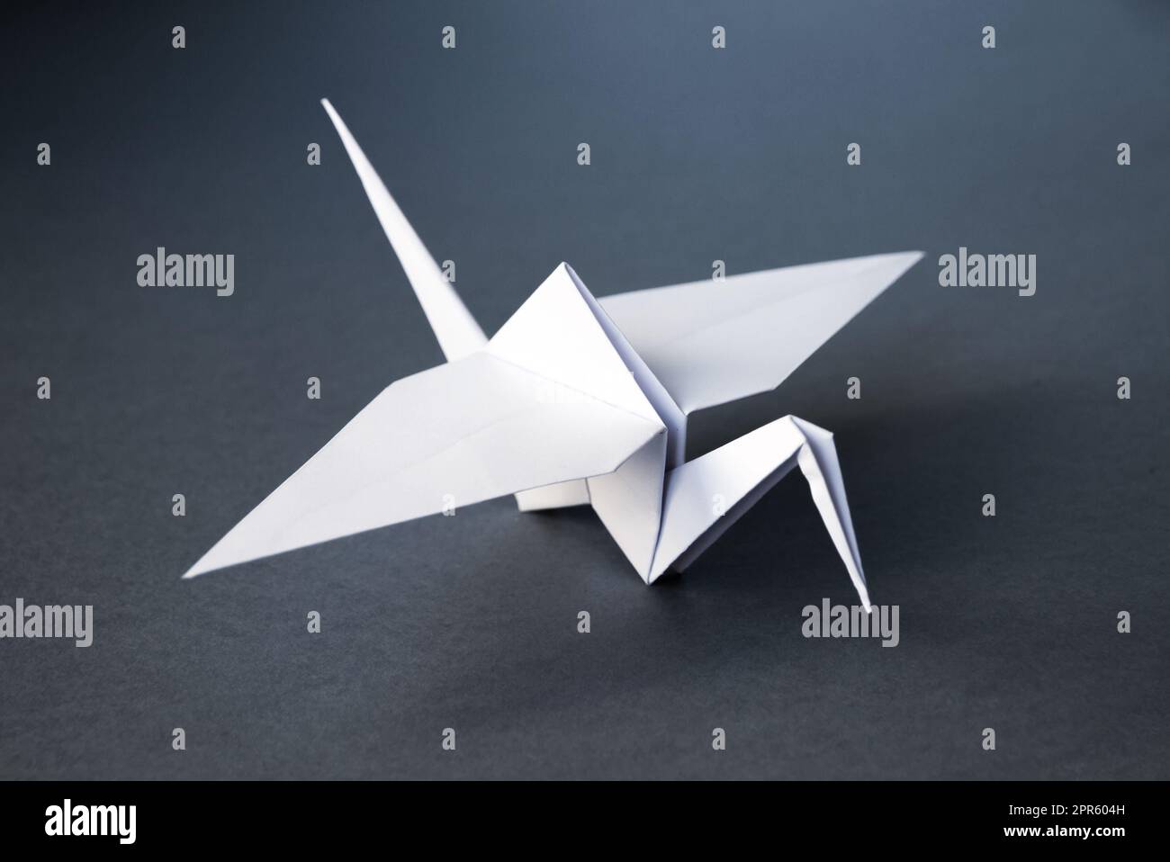 Grue à papier blanc origami isolé sur fond gris Banque D'Images