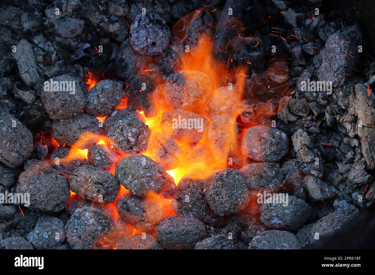 Chaleur scintillante provenant du charbon de bois incandescent pour durcir les couteaux Banque D'Images