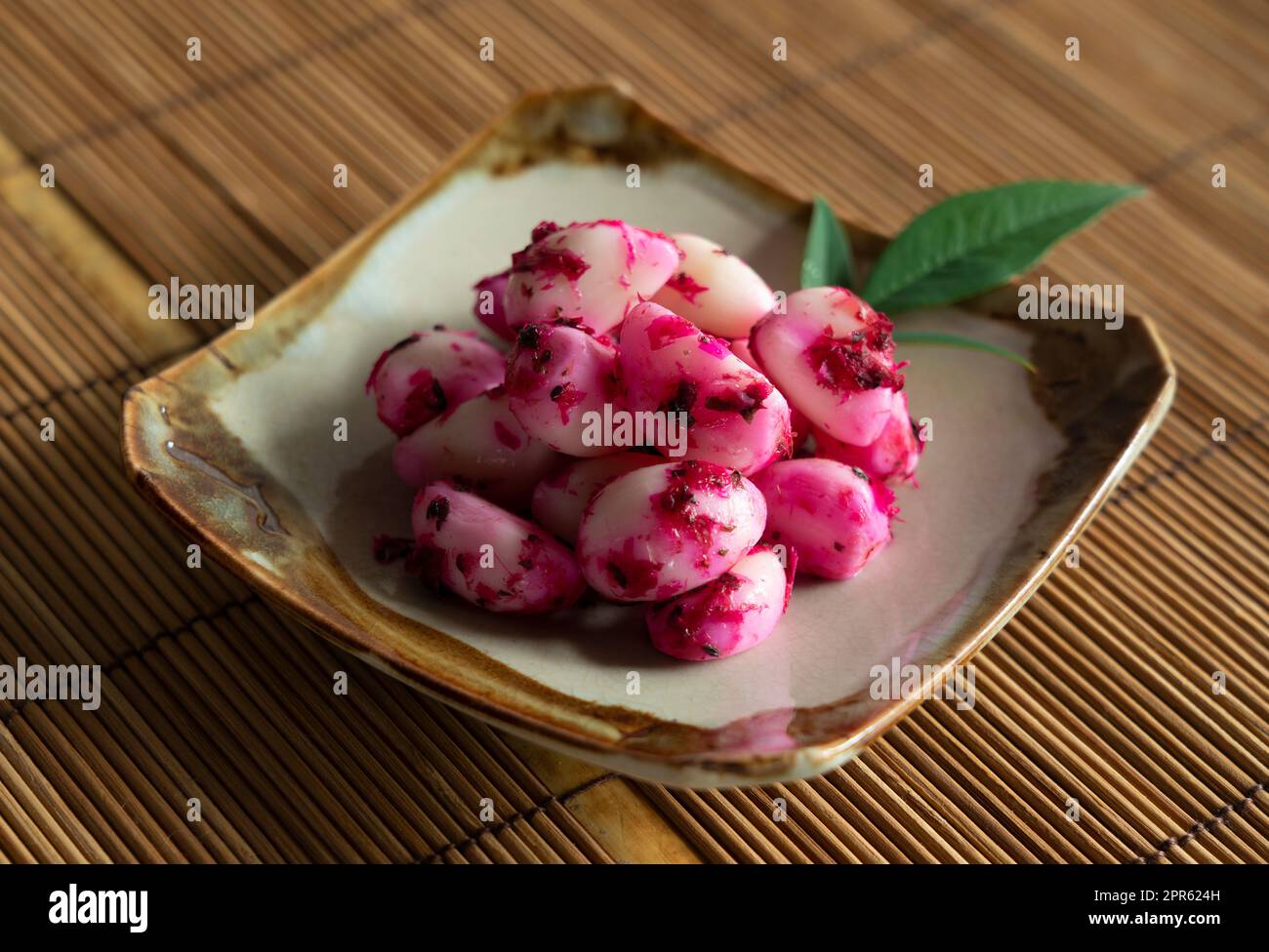 De l'ail de bonito de shiso mariné servi sur une assiette placée sur un tapis de pain en bambou. Banque D'Images