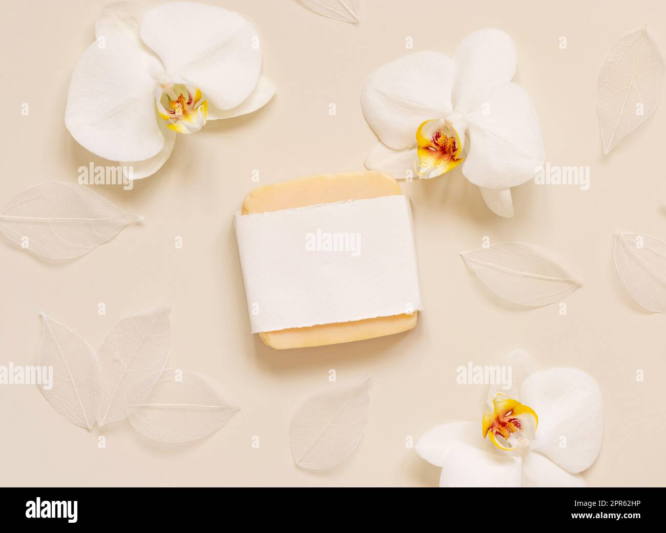 Bar à savon fait à la main près des fleurs d'orchidées blanches sur la vue de dessus jaune clair. Maquette Banque D'Images