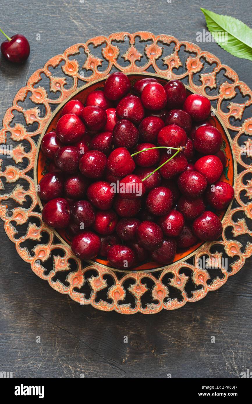 Composition de cerises douces sur une assiette avec gouttes d'eau. Concept été et récolte. Cerisier macro. Végétalien, végétarien, nourriture crue Banque D'Images