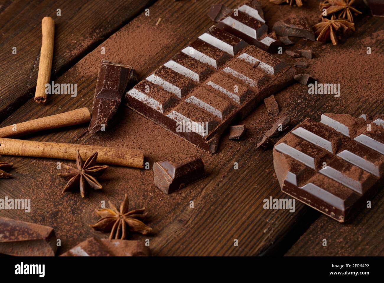 morceaux de chocolat noir cassés, bâtonnets de cannelle et anis étoilé sur une table en bois marron, vue du dessus Banque D'Images