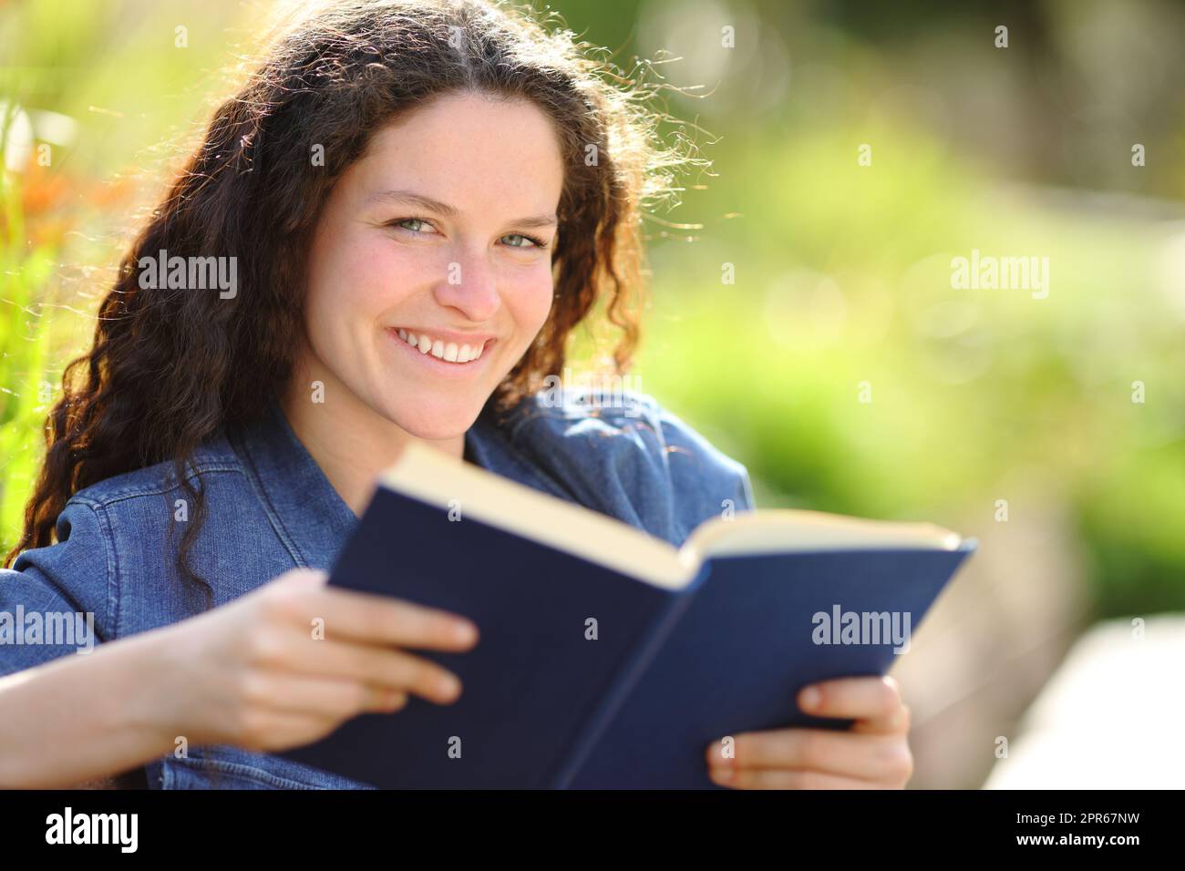 Bonne femme tenant un livre en papier regardant l'appareil photo Banque D'Images