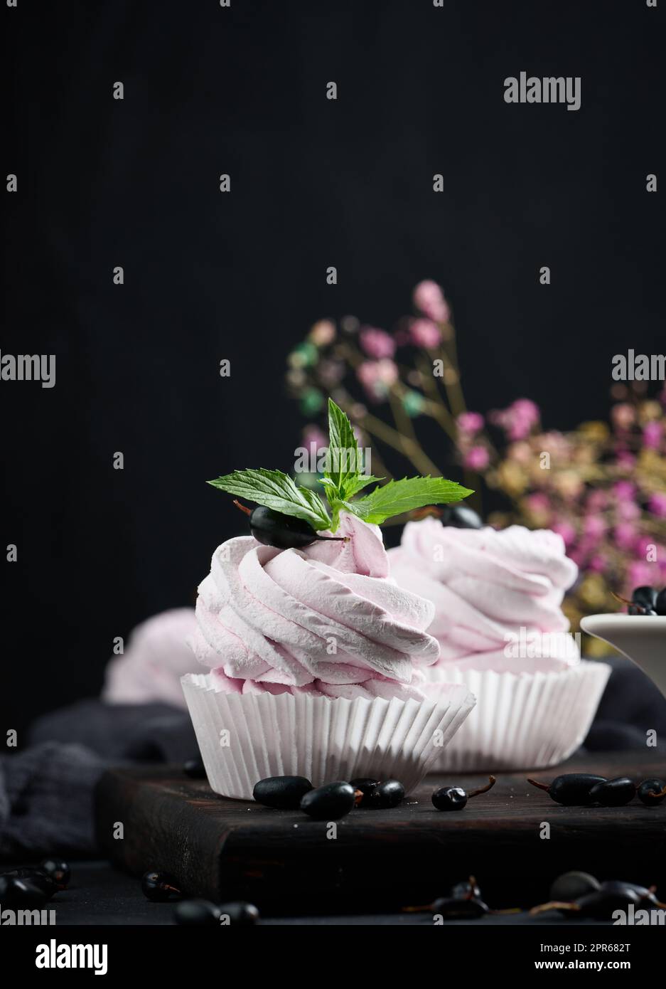 Marshmallows aux fruits dans une tasse en papier sur un panneau en bois noir Banque D'Images