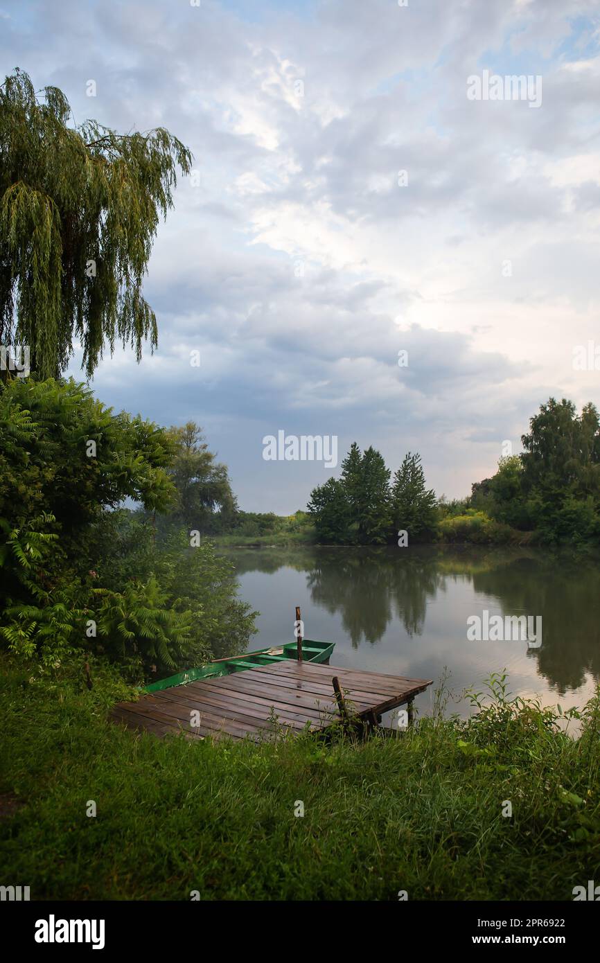 Faune, jetée avec un bateau avec des oars. Le ciel après la pluie, la fraîcheur dans l'air. Le concept de camping et de campagne est avec des tentes. Banque D'Images