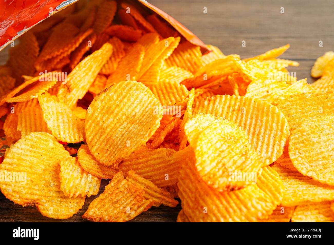 Croustilles dans un sac ouvert, délicieux assaisonnement barbecue épicé pour les pleurs, fine tranche de collation frite rapide. Banque D'Images