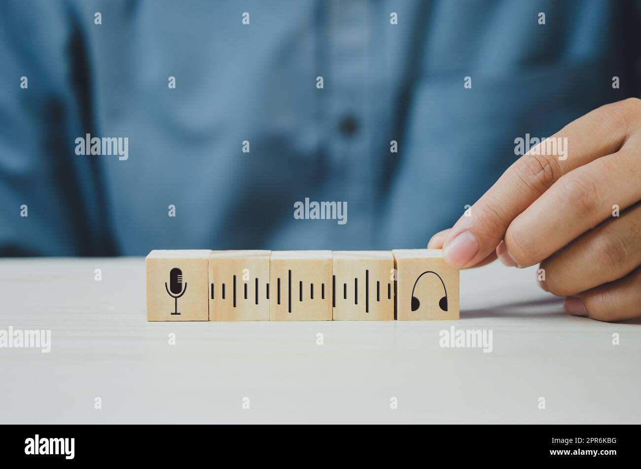 Mettez à la main des cubes en bois avec le symbole de micro Podcast et de casque sur la table et l'espace de copie.concepts d'affaires. Banque D'Images