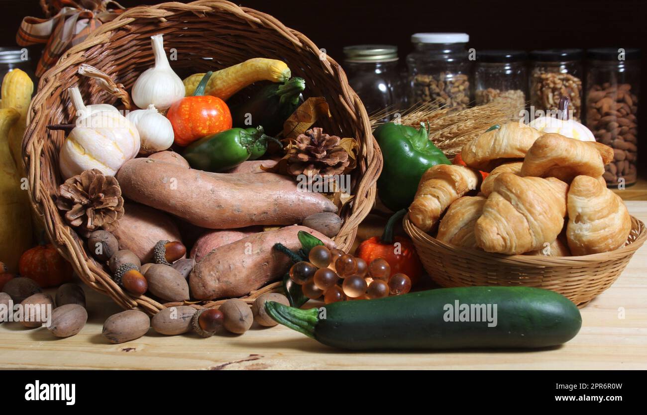 Paniers de légumes frais et de pain dans la cuisine rustique avec jarres de nourriture séchée en arrière-plan Banque D'Images