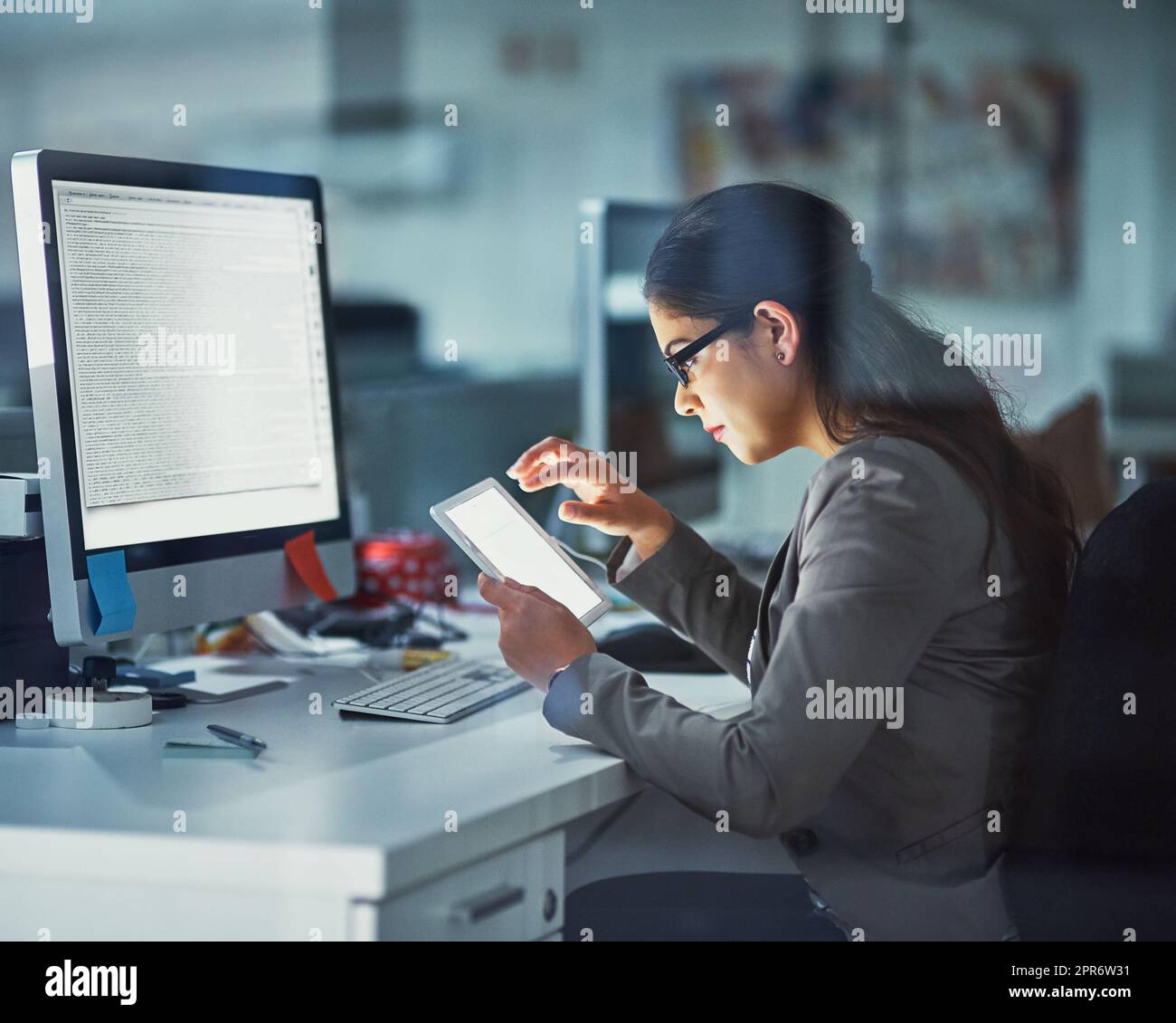 En ligne et au travail. Photo d'une jeune femme d'affaires travaillant tard au bureau. Banque D'Images