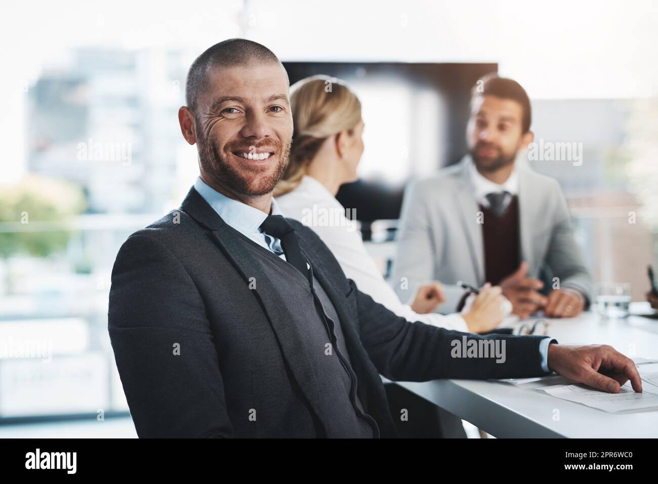 Étaient là pour faire le travail. Portrait d'un homme d'affaires mature assis dans un bureau avec ses collègues en arrière-plan. Banque D'Images