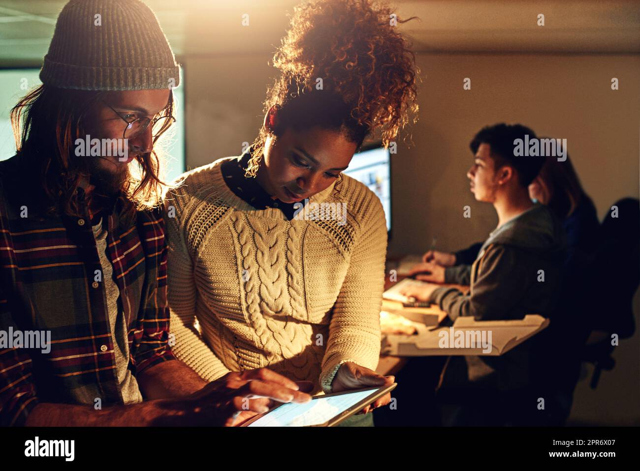 Nous nous engageons à battre chaque échéance. Photo de deux collègues discutant de quelque chose sur une tablette numérique pendant leur quart de nuit au bureau. Banque D'Images