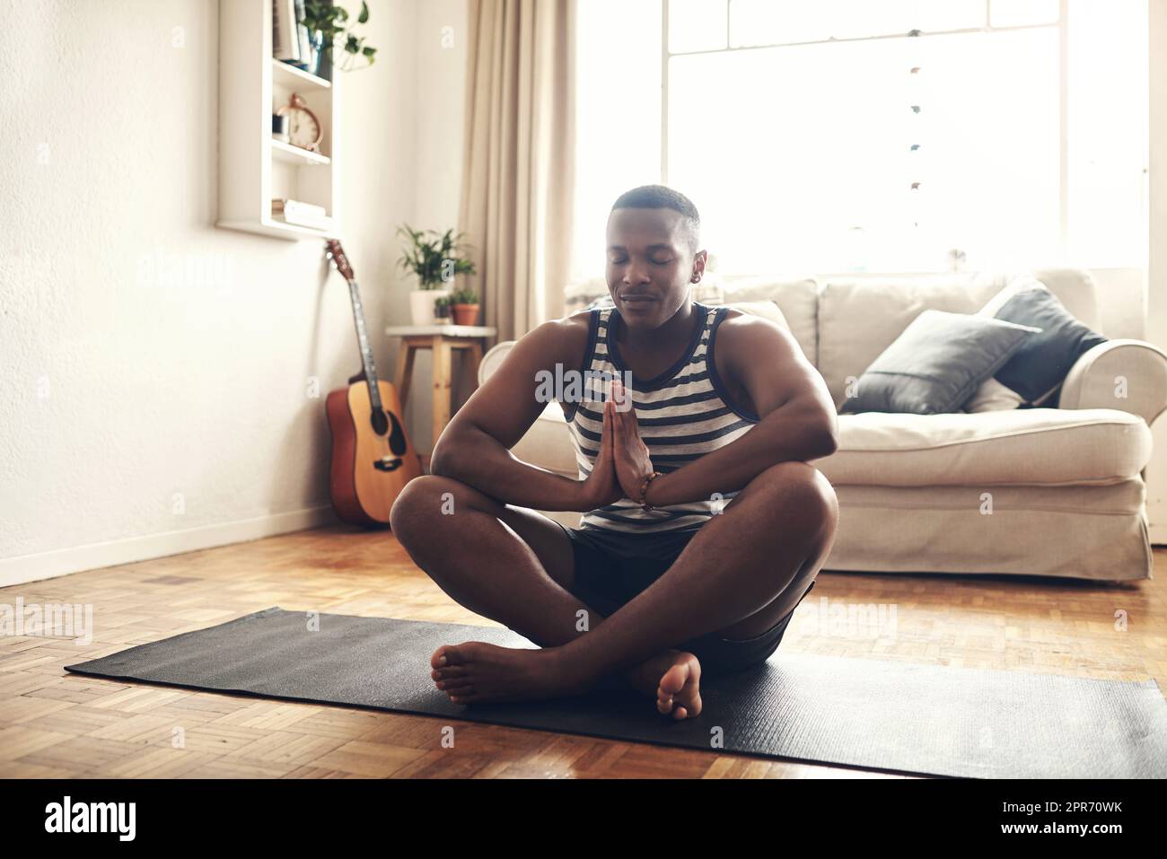 Vos pensées contrôlent votre vie. Photo d'un jeune homme sportif méditant à la maison. Banque D'Images