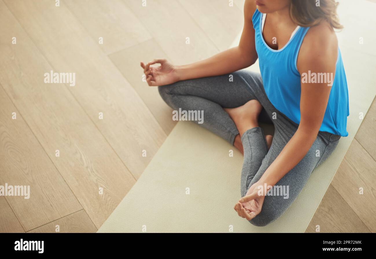 Trouver la paix intérieure. Photo en grand angle d'une jeune femme pratiquant l'art de la méditation à la maison. Banque D'Images