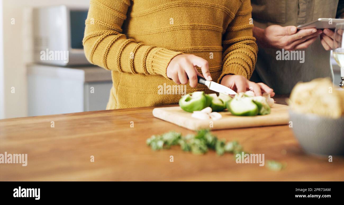 Vous ne pouvez pas battre un repas fait maison. Prise de vue rognée d'un couple à l'aide d'une tablette numérique tout en préparant un repas à la maison. Banque D'Images