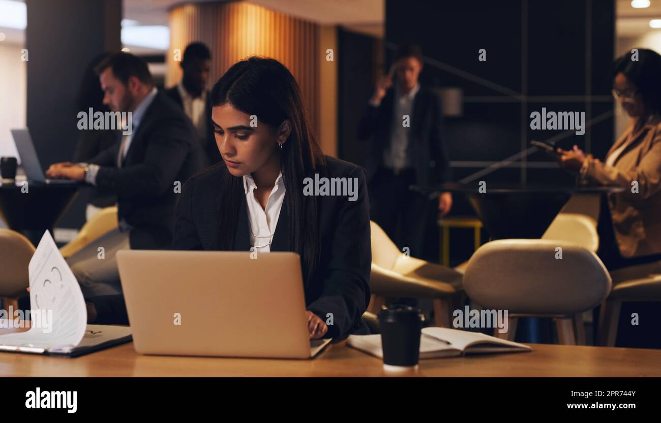 Rester en retard avec le reste de son équipe. Photo d'une jeune femme d'affaires qui travaille sur un ordinateur portable dans un bureau la nuit. Banque D'Images