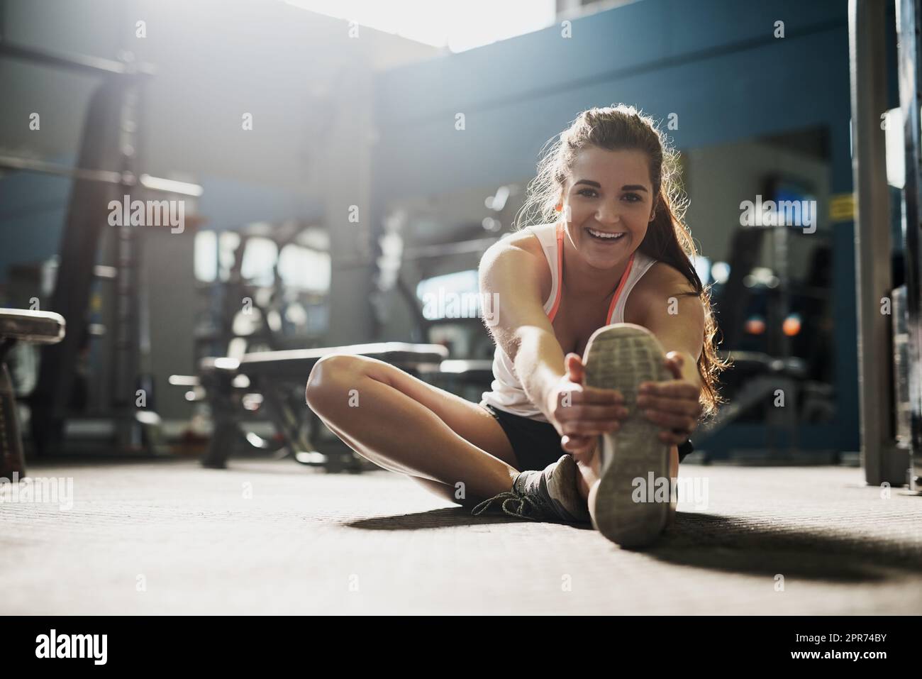 Chaque entraînement est en cours. Photo d'une jeune femme effectuant des exercices d'étirement à la salle de gym. Banque D'Images