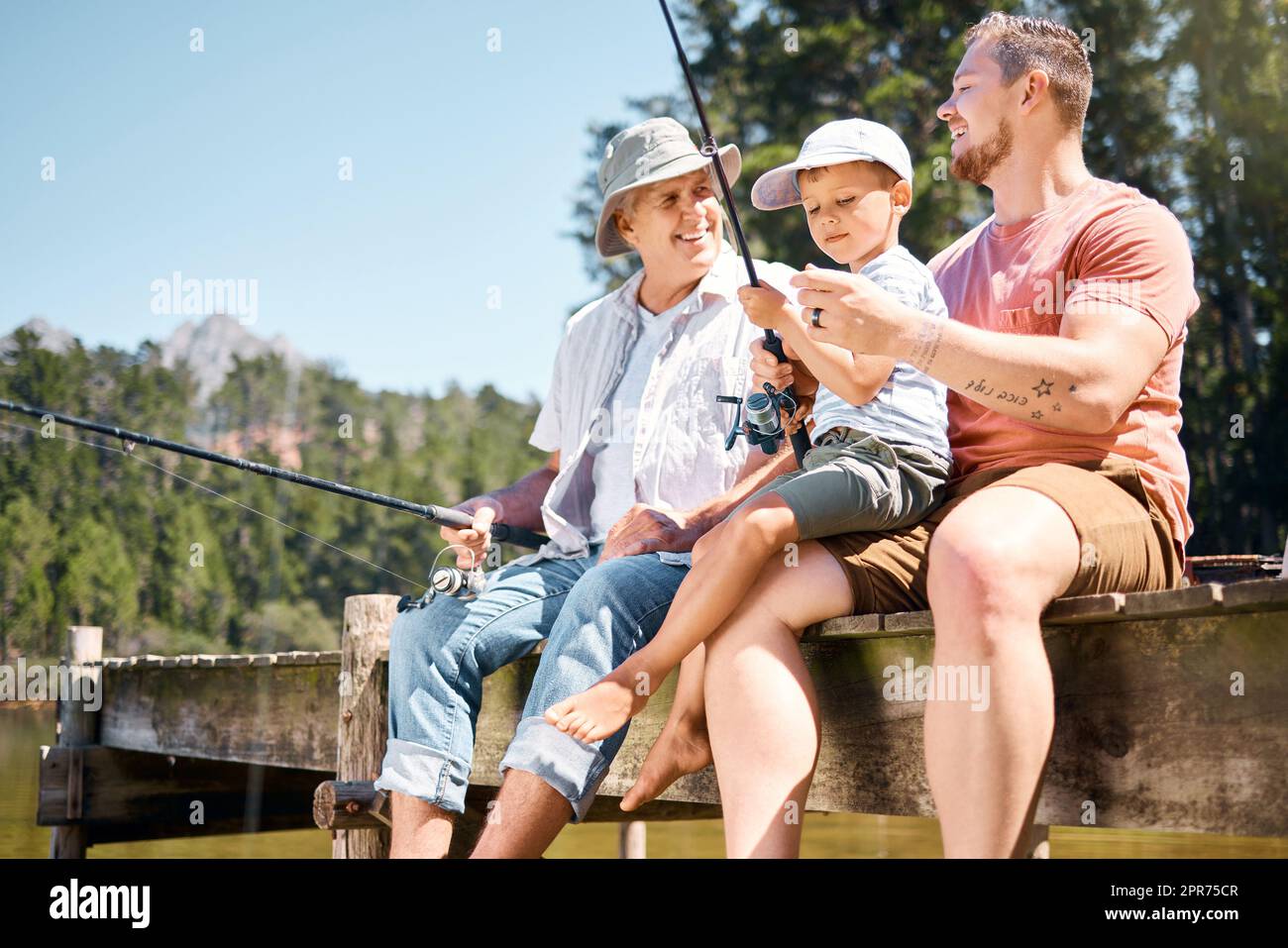 Les garçons voulaient passer du temps de qualité ensemble. Photo d'un petit garçon pêchant avec son père et son grand-père à un lac dans une forêt. Banque D'Images