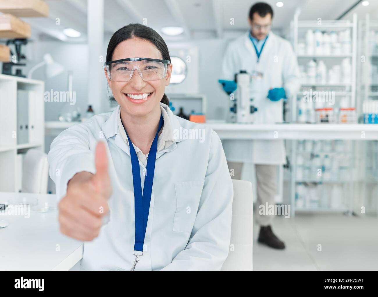 Mon expérience a été un succès ardu. Portrait d'un jeune scientifique montrant les pouces dans un laboratoire. Banque D'Images