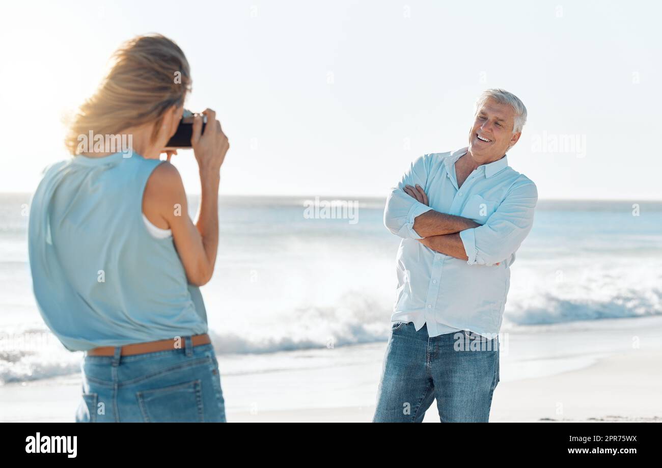 Après toutes ces années, je suis encore écrasant. Photo d'une femme prenant une photo de son mari à la plage. Banque D'Images