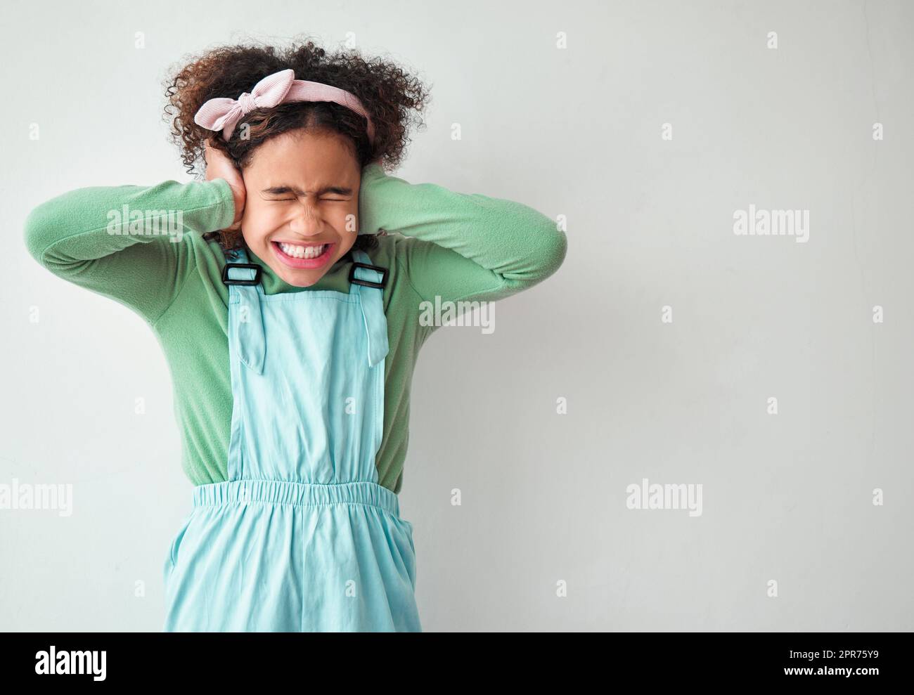 Les petites filles apportent un tel plaisir. Photo d'une jeune fille couvrant ses oreilles sur fond gris. Banque D'Images