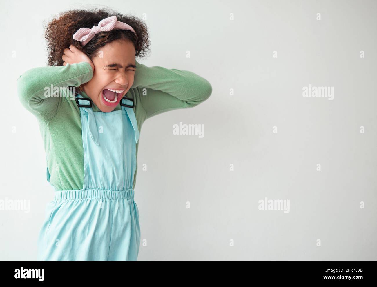 Les petites filles sont des cadeaux précieux. Photo d'une jeune fille couvrant ses oreilles sur fond gris. Banque D'Images
