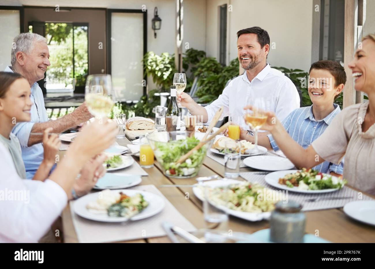 Partagez un toast. Photo d'une famille partageant un toast tout en dégustant un repas ensemble. Banque D'Images