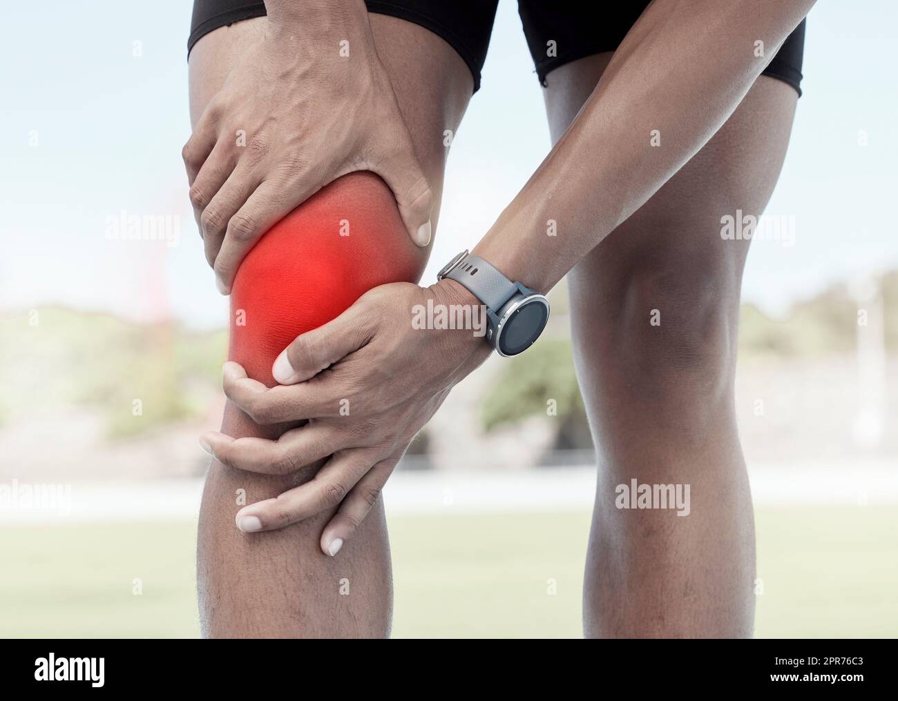 Gros plan d'un sportif tenant un genou douloureux en rouge éclatant. Un athlète mal à l'aise souffrant d'une blessure douloureuse à la jambe s'est fracturé l'articulation et a enflammé les muscles pendant l'entraînement. Déformation due à un effort excessif Banque D'Images