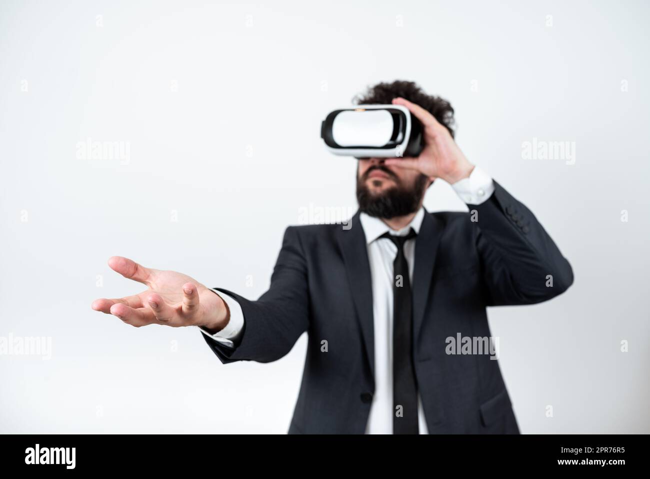 Homme portant des lunettes VR et présentant des messages importants d'une main. Homme d'affaires ayant des lunettes de réalité virtuelle et montrant des informations crutiales au-dessus de Palm. Banque D'Images