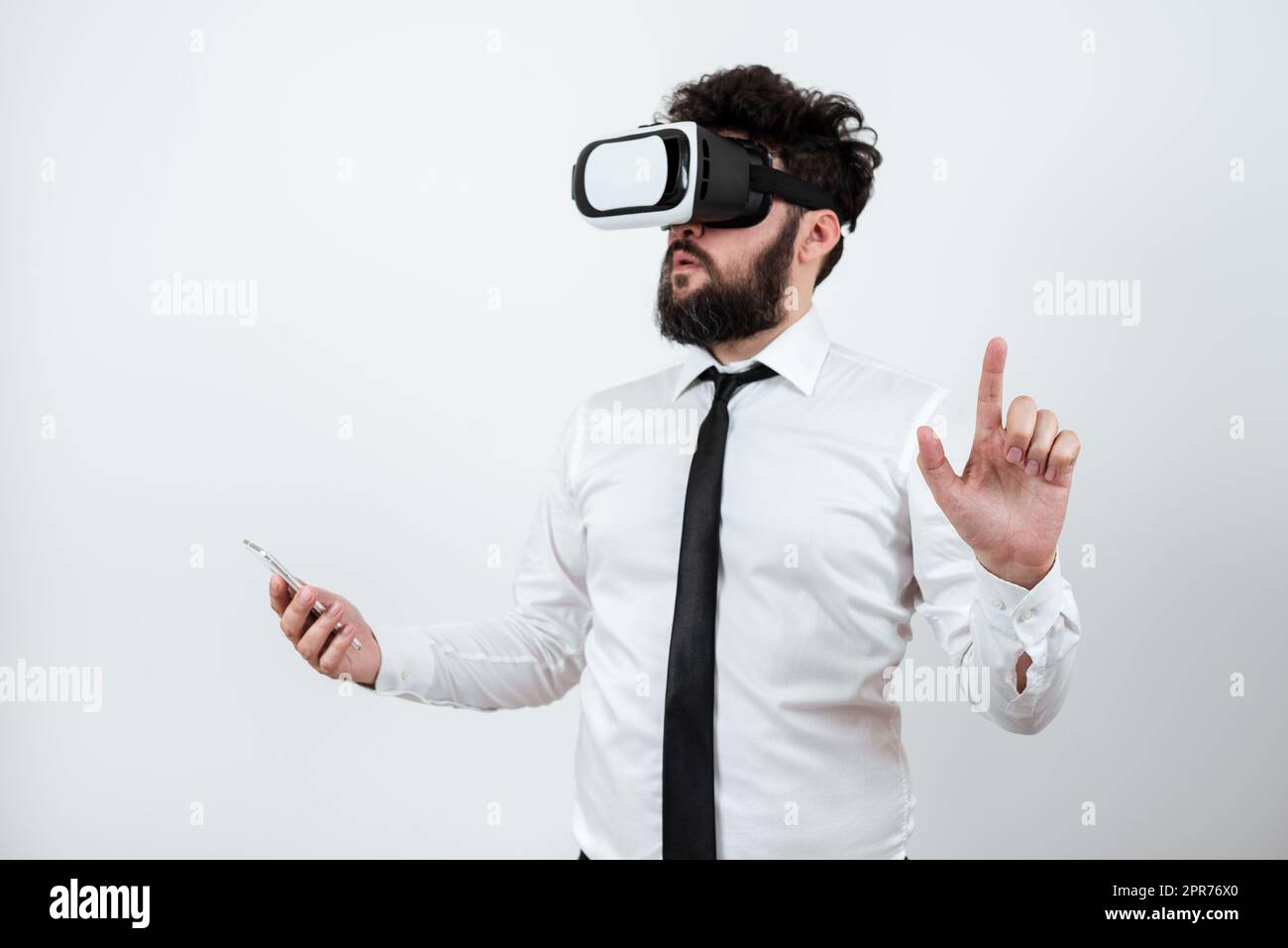 Homme tenant un téléphone portable, portant des lunettes VR et pointant d'un doigt sur les dernières mises à jour. Homme d'affaires ayant des lunettes de réalité virtuelle, le téléphone portable et la présentation de Nouvelle idée. Banque D'Images
