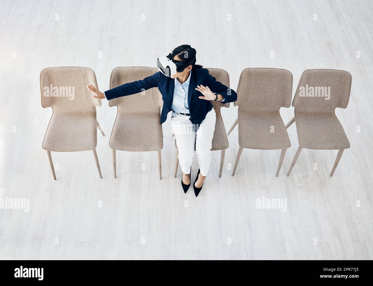 Immergée dans un monde nouveau. Prise de vue en grand angle d'une jeune femme d'affaires portant un casque VR tout en étant assise dans la ligne d'un bureau. Banque D'Images