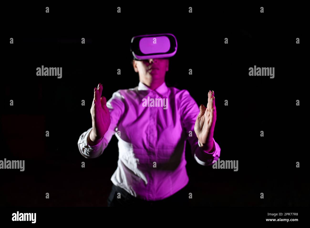 Femme d'affaires utilisant des lunettes de réalité virtuelle gestant tout en suivant une formation professionnelle. La lumière tombe sur une femme portant un simulateur moderne et présentant la technologie créative Banque D'Images