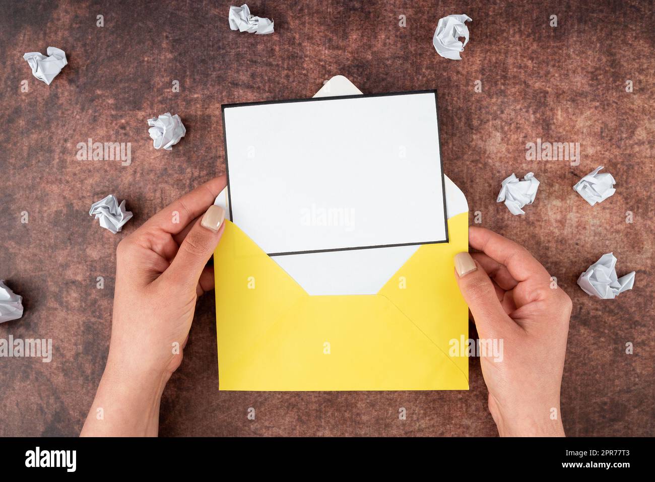 Mains de la femme d'affaires tenant la feuille vierge et l'enveloppe entourée de papier froissé sur le bois. Femme avec une lettre montrant un message crucial. Espace vide pour la publicité. Banque D'Images