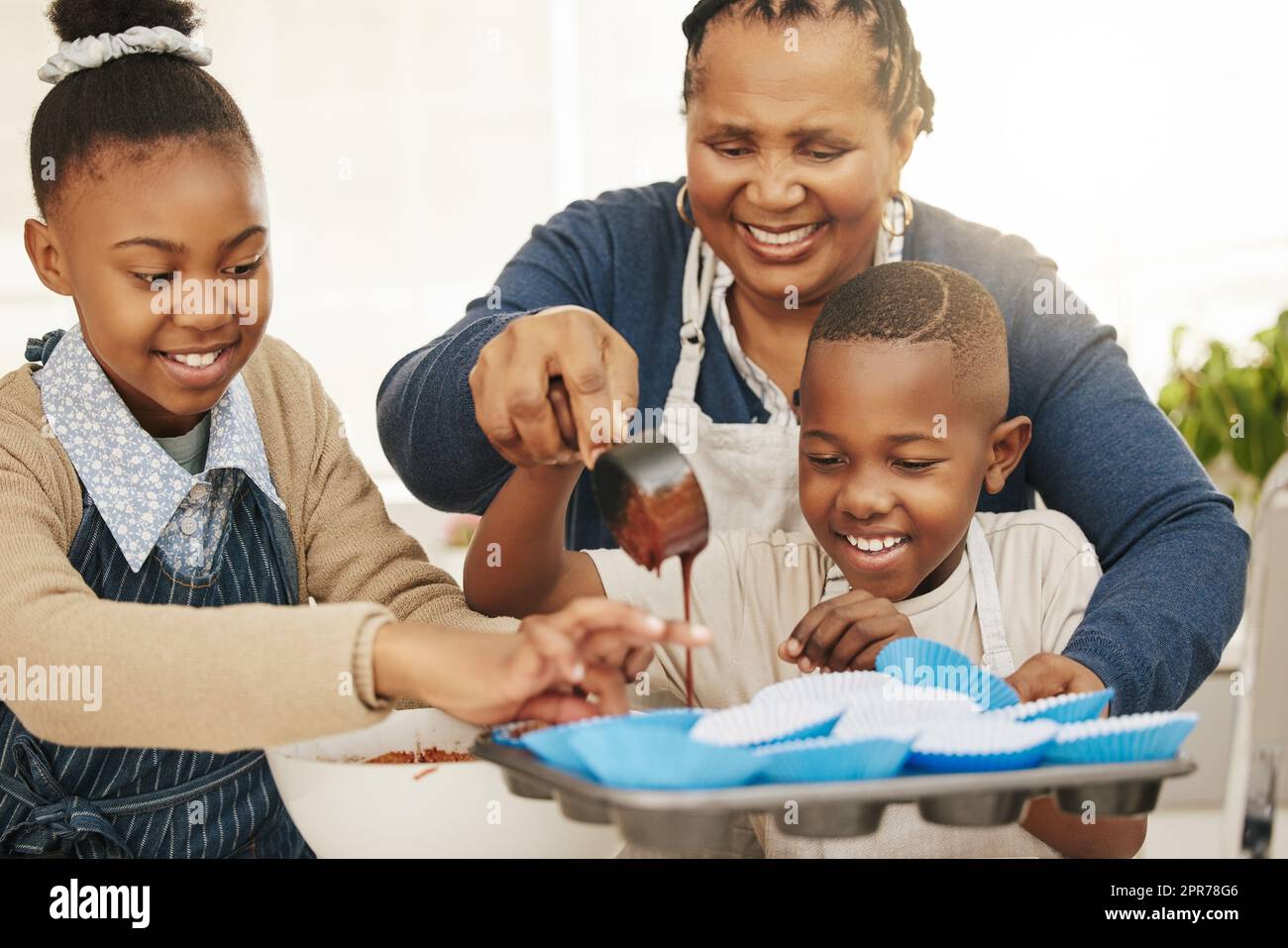 Bien faire plus à emporter à la maison. Photo d'une grand-mère qui cuit avec ses deux petits-enfants à la maison. Banque D'Images