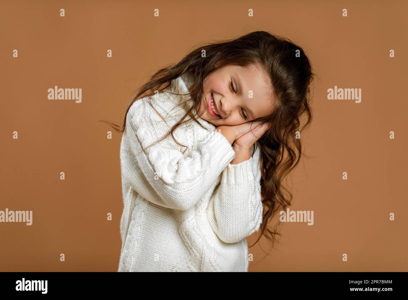 petite fille d'enfant dans le chandail blanc fait le geste de sommeil Banque D'Images