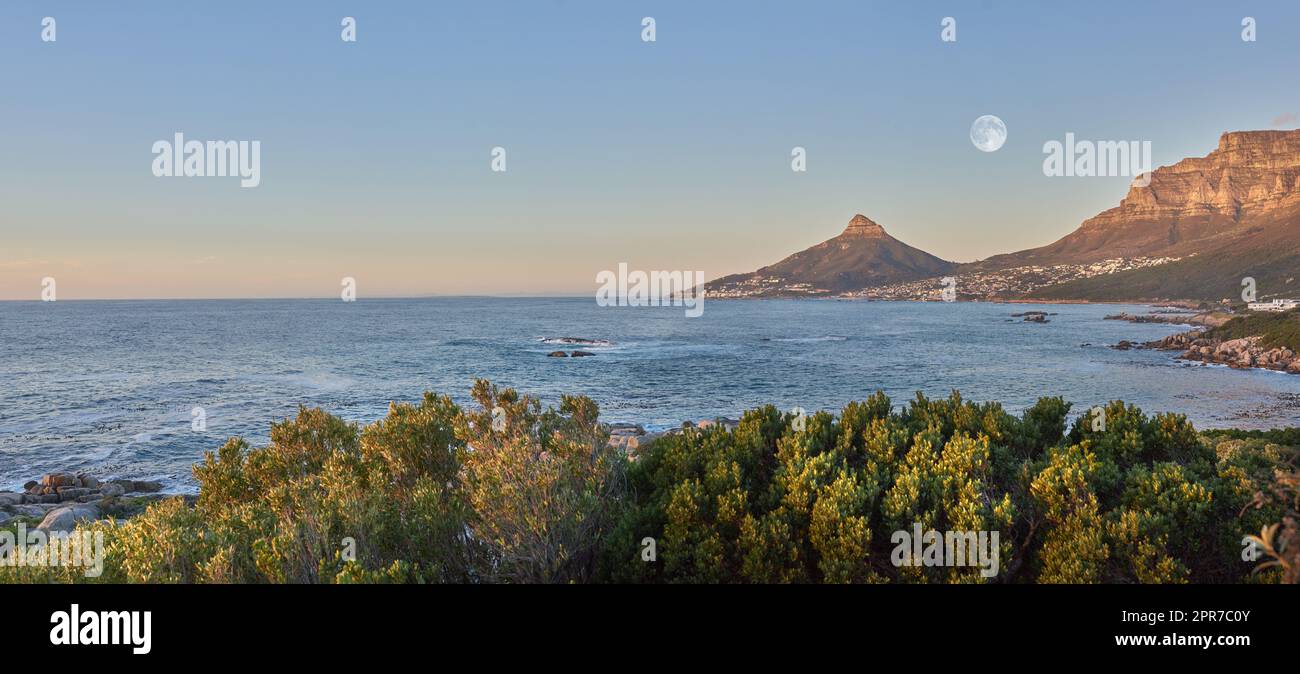 Vue panoramique sur l'eau de mer, les montagnes et le ciel bleu avec espace de copie de Lions Head et de la montagne de la Table au Cap, Afrique du Sud. Calme, serein, tranquille, océan et détente paysage de nature au lever du soleil Banque D'Images