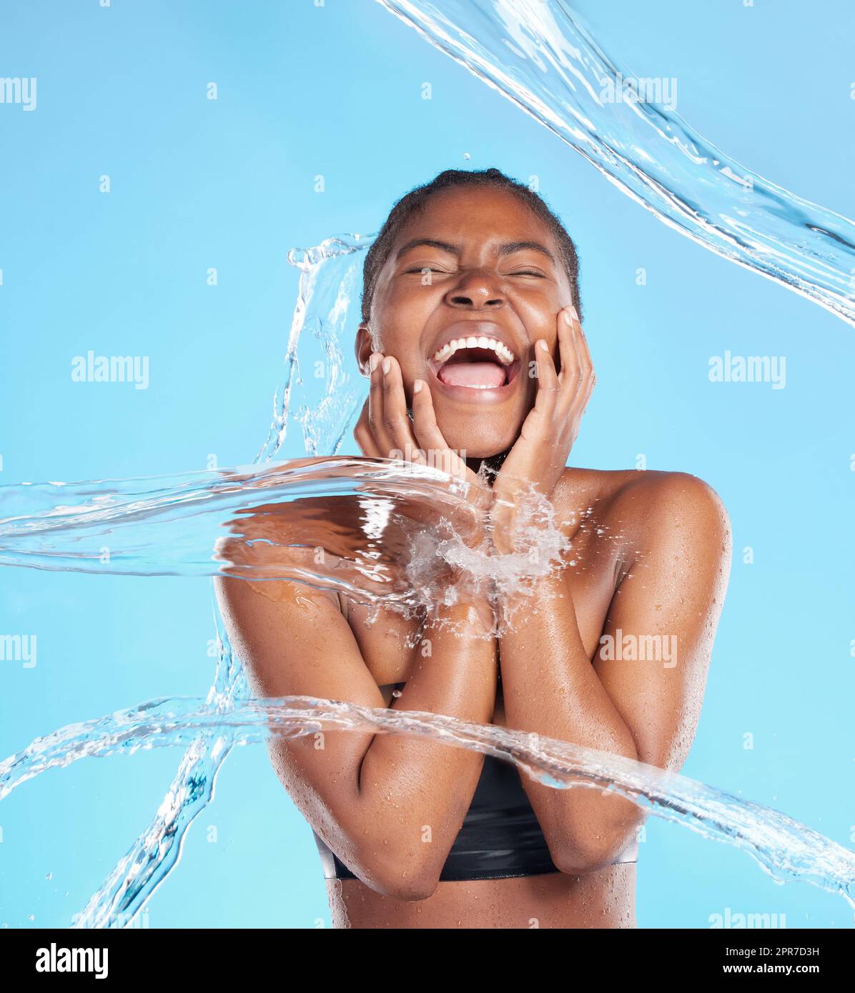 Sentez-le devenir plus humide. Photo d'une belle jeune femme éclaboussé avec de l'eau sur un fond bleu. Banque D'Images