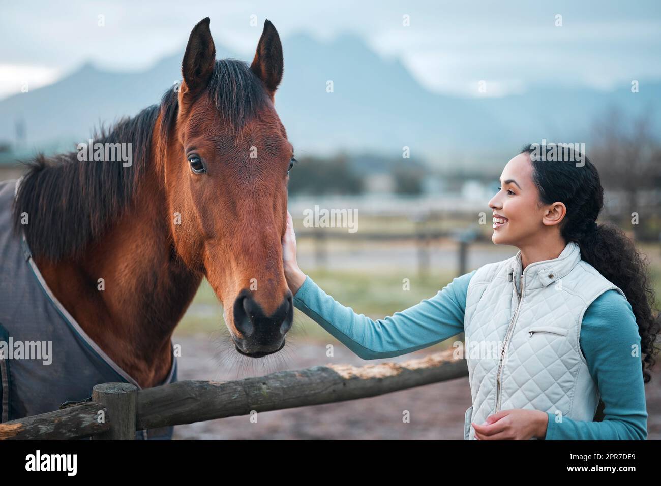 Sortez d'ici. Une femme attrayante posant avec un cheval dans un pâturage clos sur une ferme. Banque D'Images