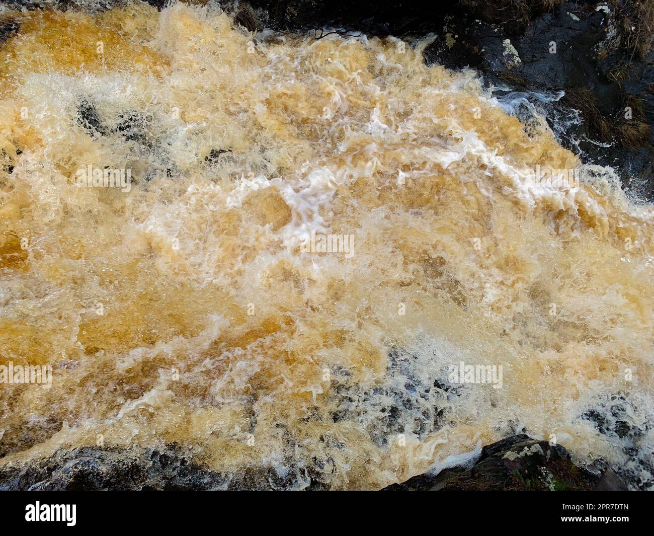 De l'eau jaune brune coule dans un flux moussant bouillant Banque D'Images