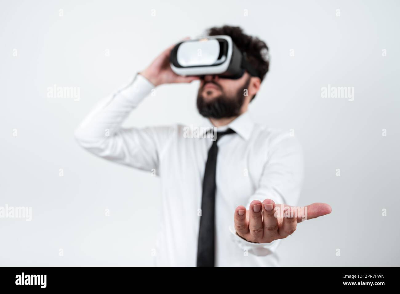 Homme portant des lunettes VR et présentant des messages importants d'une main. Homme d'affaires ayant des lunettes de réalité virtuelle et montrant des informations crutiales au-dessus de Palm. Banque D'Images